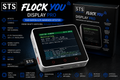 STS Flock You Display Pro touchscreen alarm awareness detector shown with its retail box on a dark promotional background. The device has a white and silver body with a lit display and red control buttons, surrounded by feature callouts and product specs.